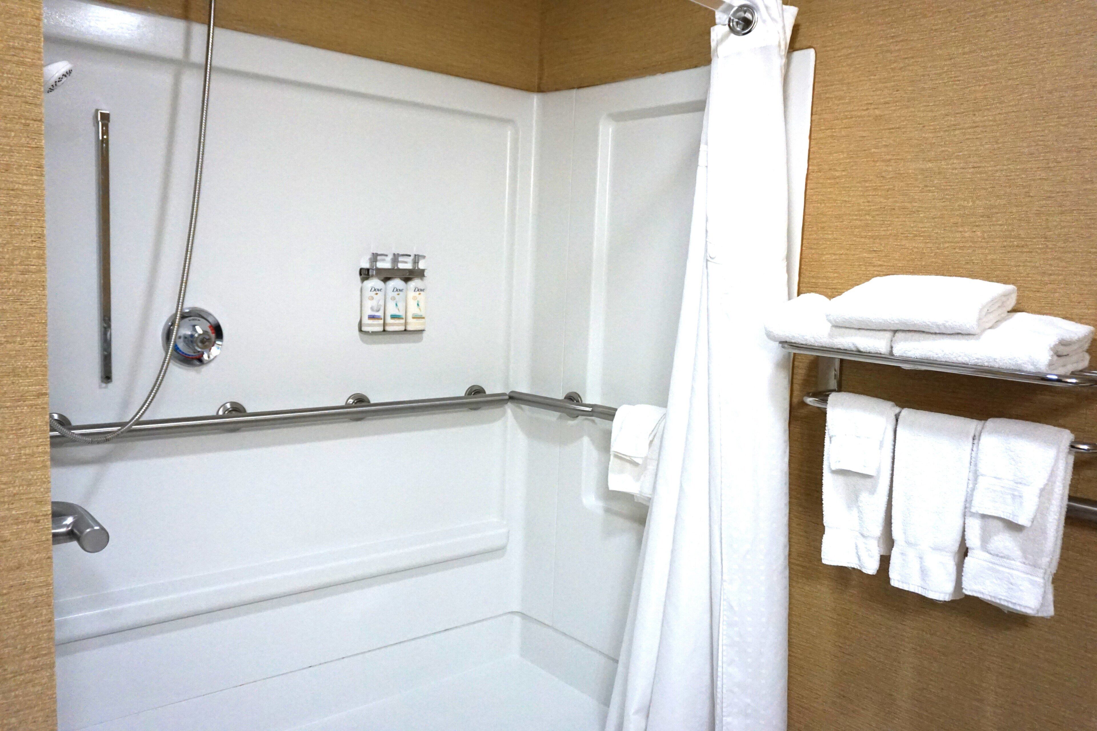 Un baño con ducha, un perchero y un estante con toallas dobladas.