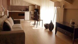 A modern living room with a sofa, a dining area, and a kitchen in the background. - Athens Habitat (Marousi)