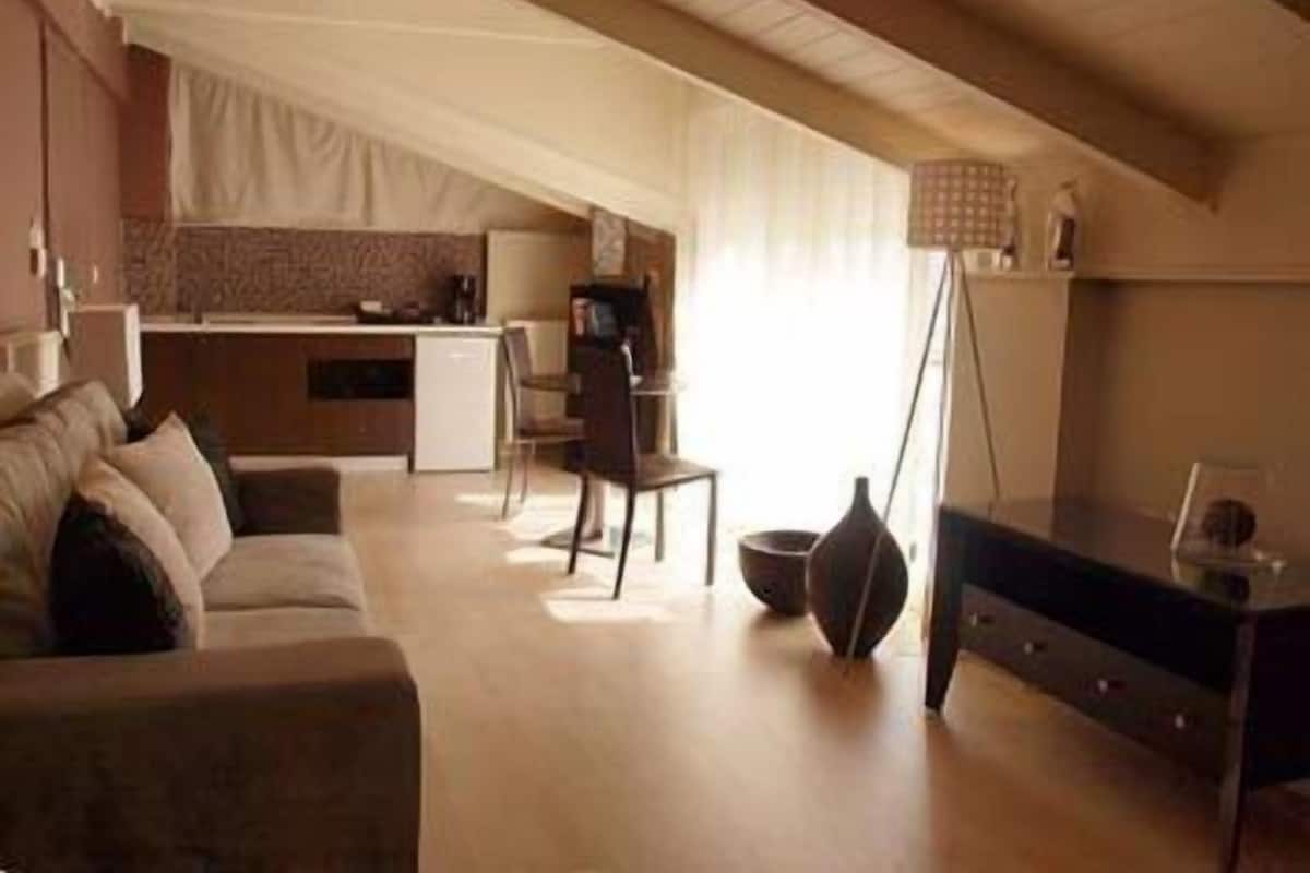 Un salon moderne avec un canapé, un coin repas et une cuisine en arrière-plan.