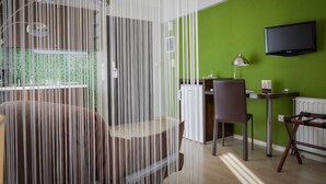 A modern kitchen with a green wall, a flat-screen TV, and a dining area with a table and chairs. - Athens Habitat (Marousi)
