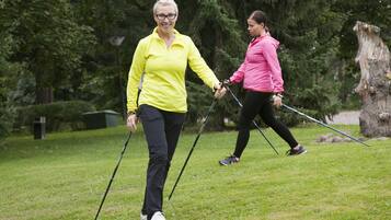 Two people walking on a grassy path in a park with trees in the background.