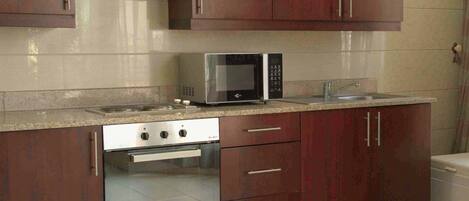 Una cocina con estufa, microondas, horno y armarios.