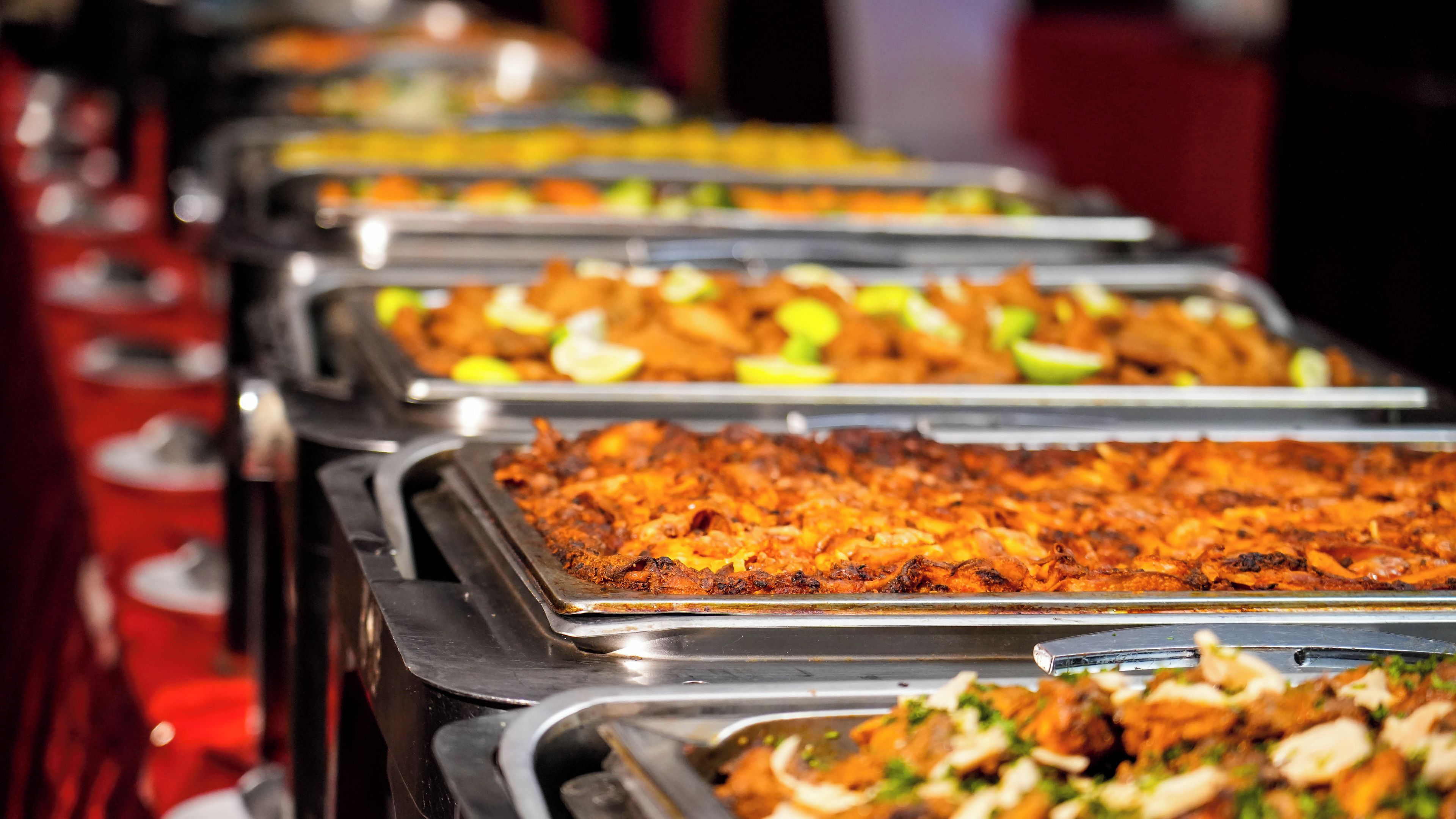 A buffet with various dishes arranged in trays.