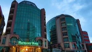 A modern hotel with a curved glass facade and a neon sign reading "Harmony Hotel". - Harmony Hotel (Addis Ababa)