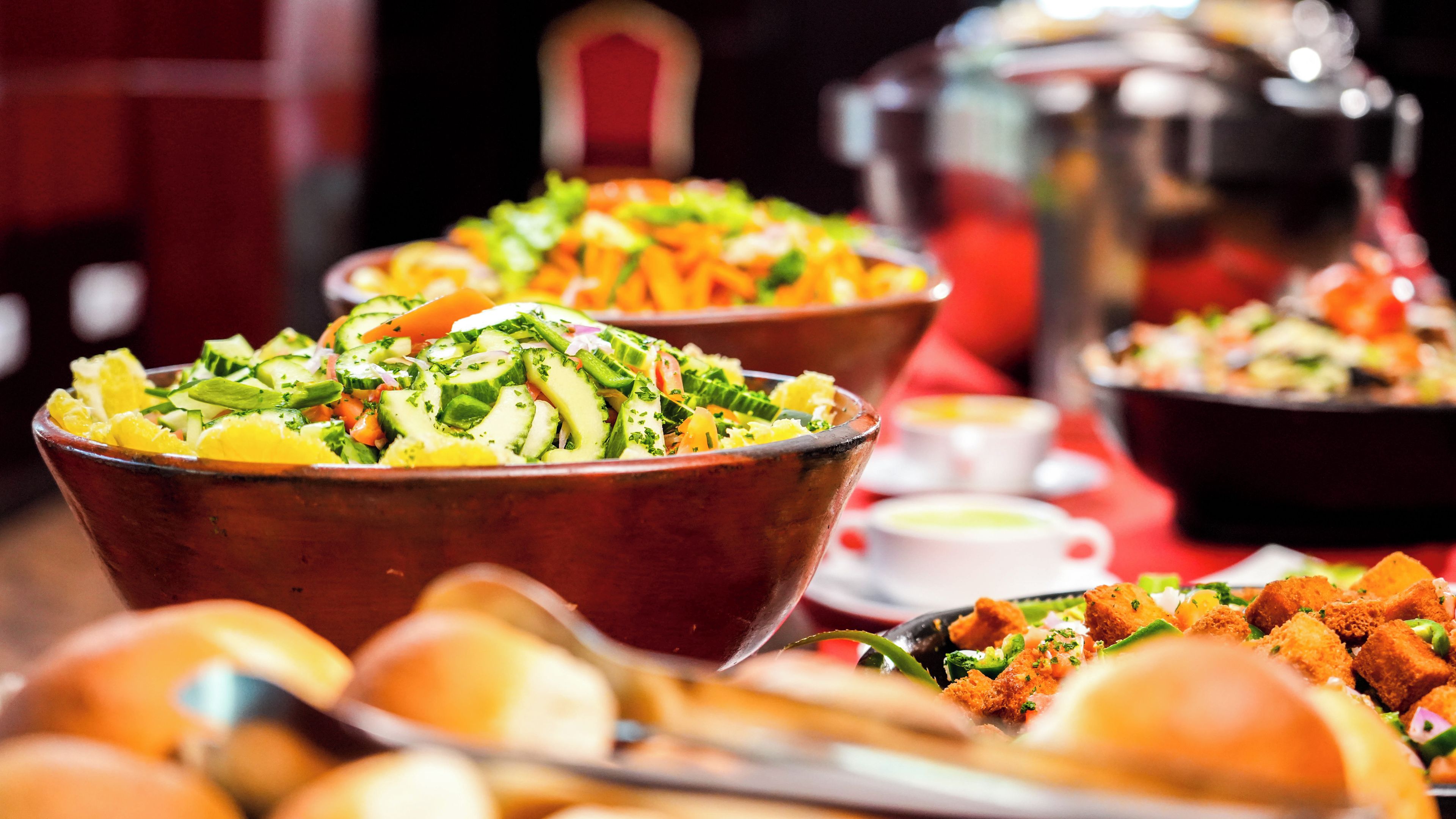 Taula de buffet amb diversos plats, incloent amanides, pa i altres aliments.