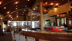 A bar area with wooden chairs and tables, a curved ceiling with lights, and large windows allowing natural light. - Harmony Hotel (Addis Ababa)