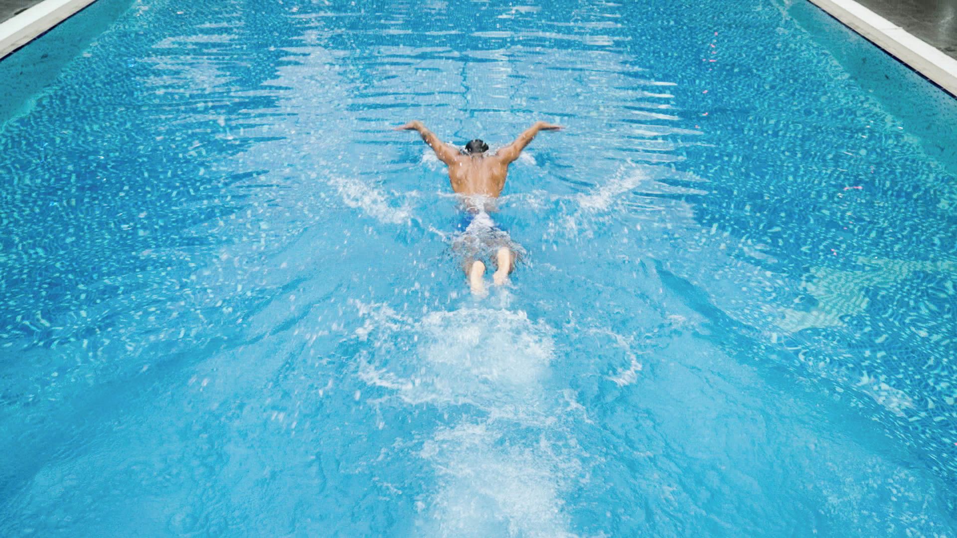 Una persona nadando en una piscina con agua cristalina azul.