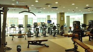 A gym with various exercise equipment, including treadmills, stationary bikes, and weight machines. - Harmony Hotel (Addis Ababa)