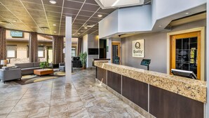 A hotel reception area with a marble counter, sofas, and a sign for 'Quality Inn & Suites.'