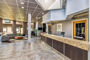 A hotel reception area with a marble counter, sofas, and a sign for 'Quality Inn & Suites.' - Quality Inn & Suites (High Level)