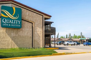 A building with a sign for 'Quality Inn & Suites' and a parking lot with vehicles.