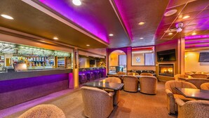 A bar area with seating, a fireplace, and a television screen.