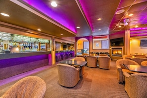 A bar area with seating, a fireplace, and a television screen. - Quality Inn & Suites (High Level)