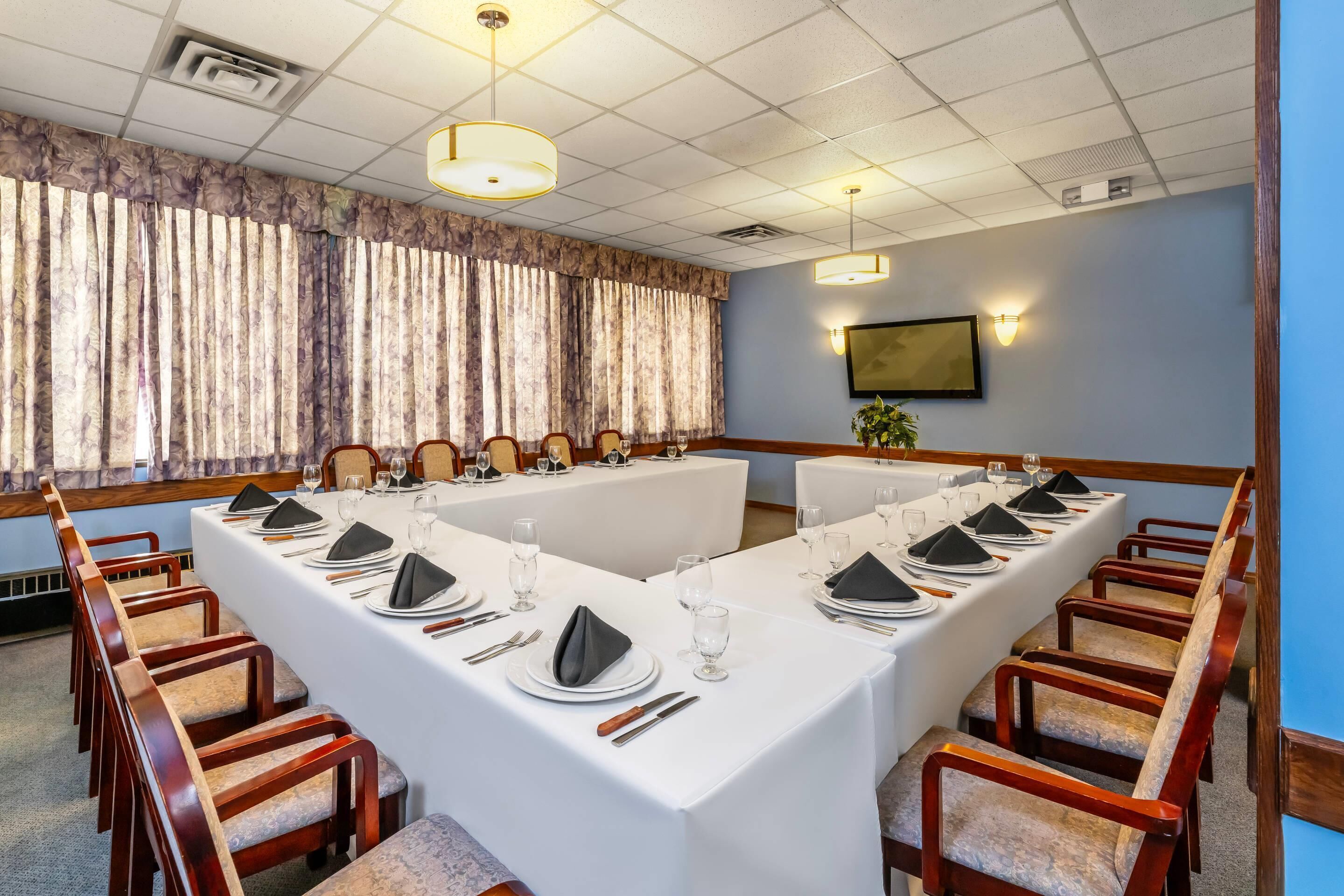 A conference room with a long table, chairs, and a television on the wall.