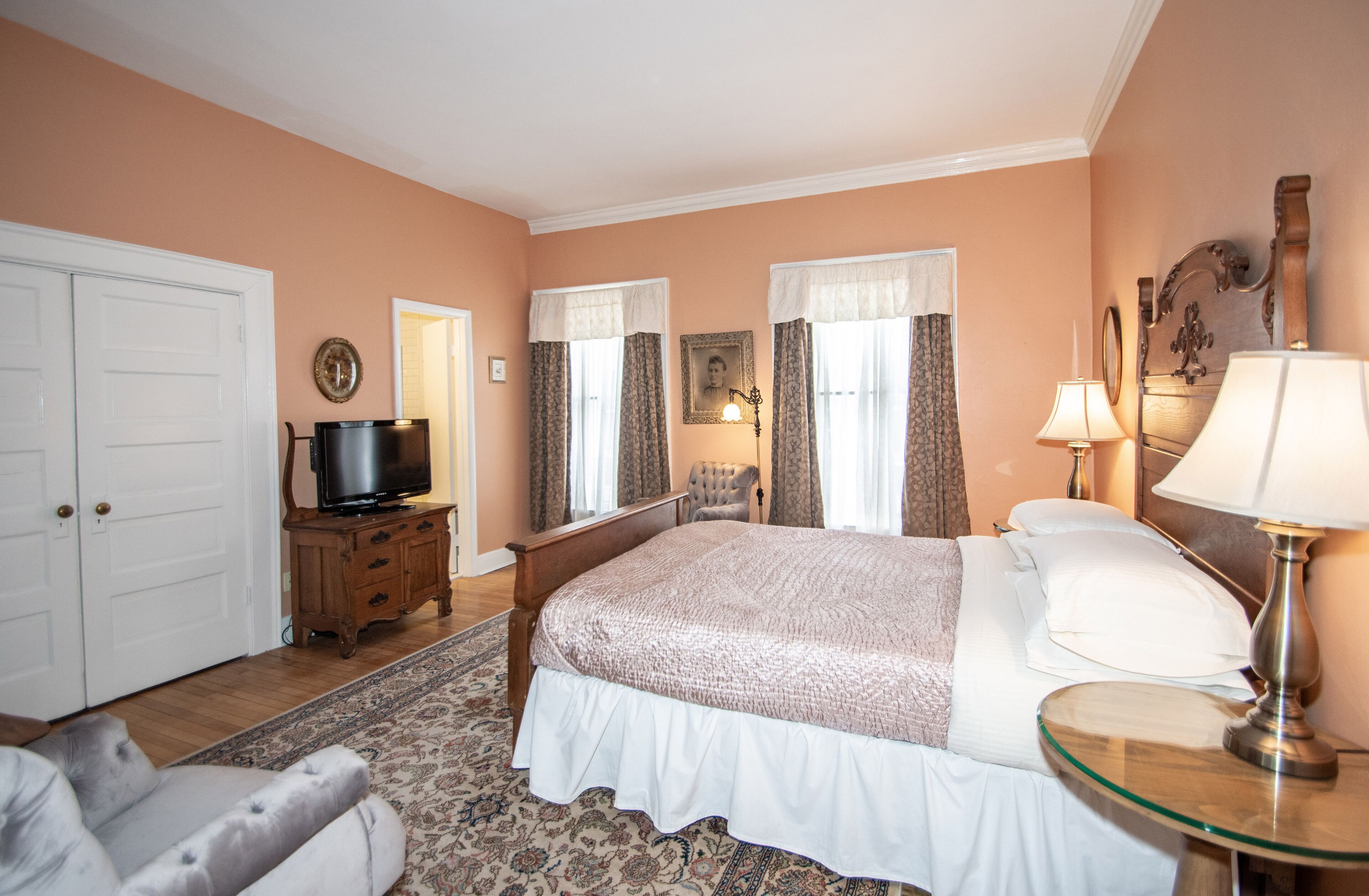 A bedroom with a bed, a television, a chair, a lamp, and a dresser.