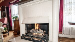 A fireplace with a burning fire, a wooden mantel, and a white brick surround. - Looking Glass Inn (Indianapolis)