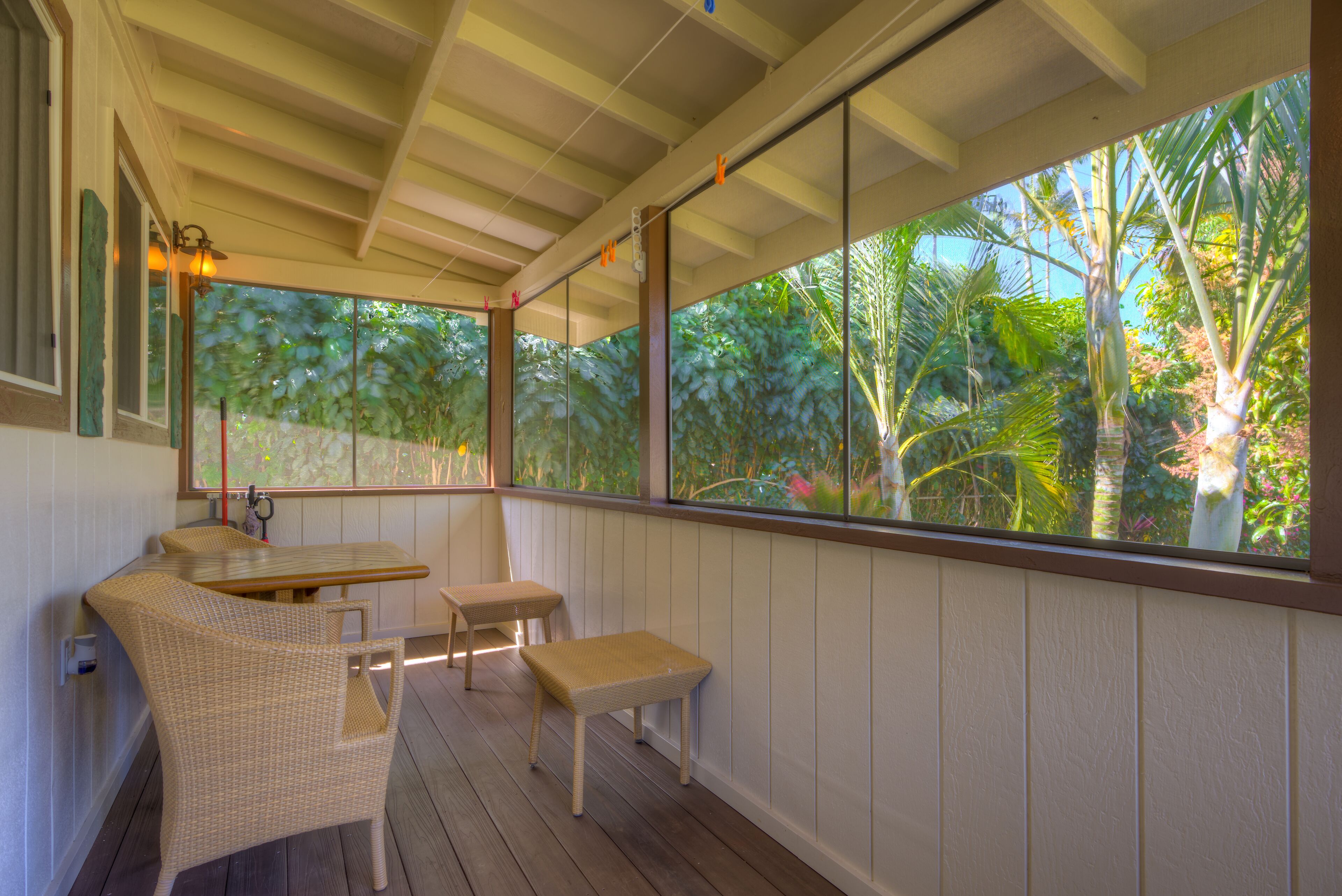 Un espace extérieur aménagé, abrité et doté de mobilier en osier, offrant une vue sur la végétation tropicale.