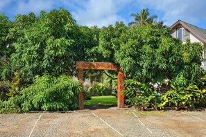 A garden entrance with a wooden archway, surrounded by lush greenery and a clear sky. - Fern Grotto Inn (Kapaa)