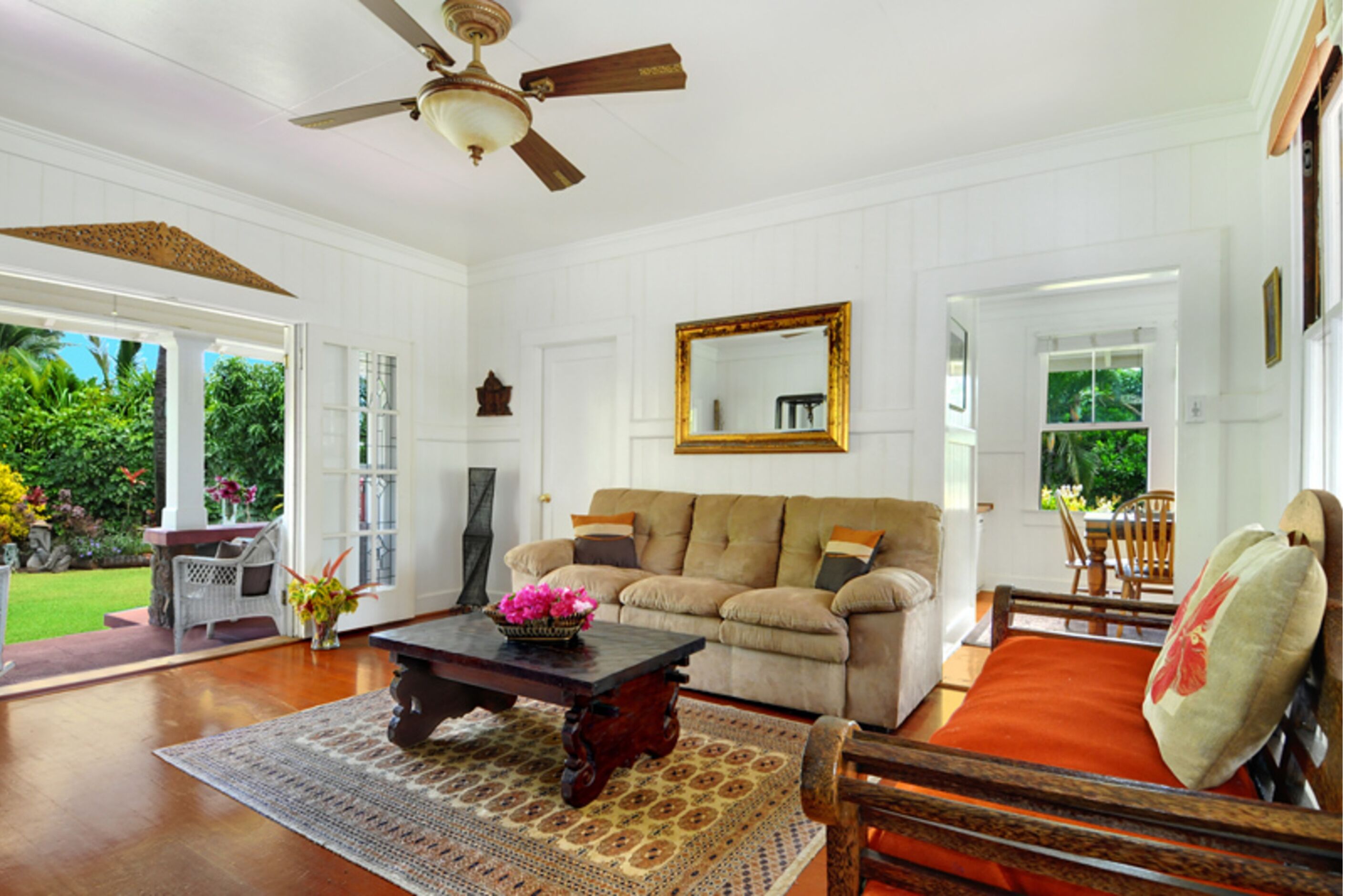 A spacious living room with a ceiling fan, a large window, and a view of the outdoors.