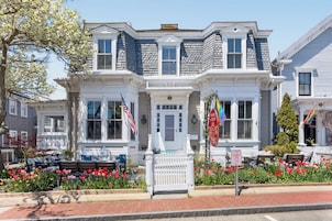 Una casa de estilo victoriano con fachada blanca, numerosas ventanas y un porche delantero.