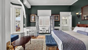 Une chambre dotée d’un grand lit, d’un coin salon avec une table et des chaises, et offrant une vue sur la salle à manger par une porte.