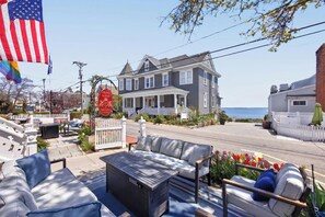 A two-story house with a porch, a flag, and a view of the ocean. - Prince Albert Provincetown (Provincetown)