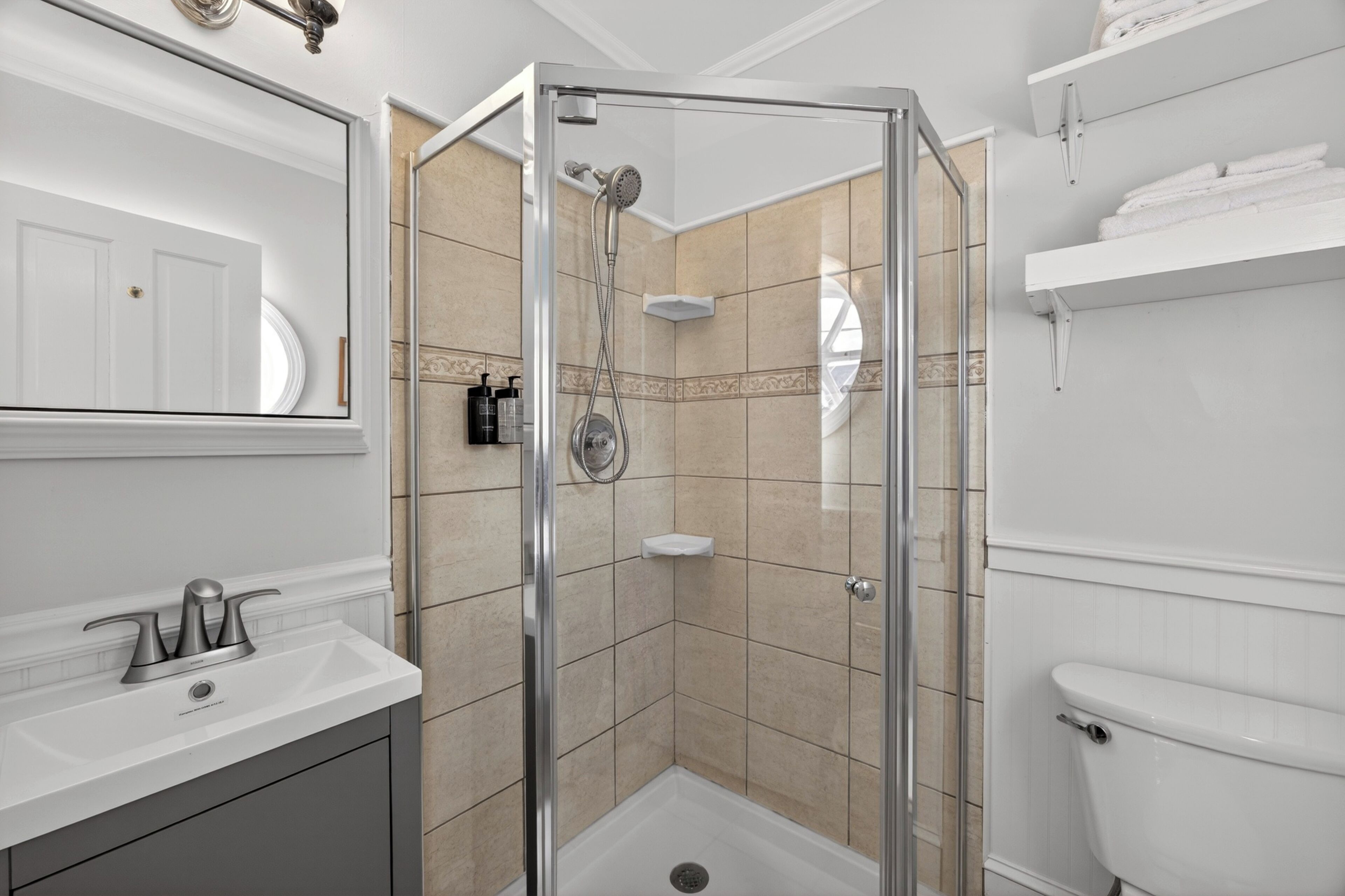 Une salle de bain avec une douche à parois de verre, un lavabo blanc et des toilettes.