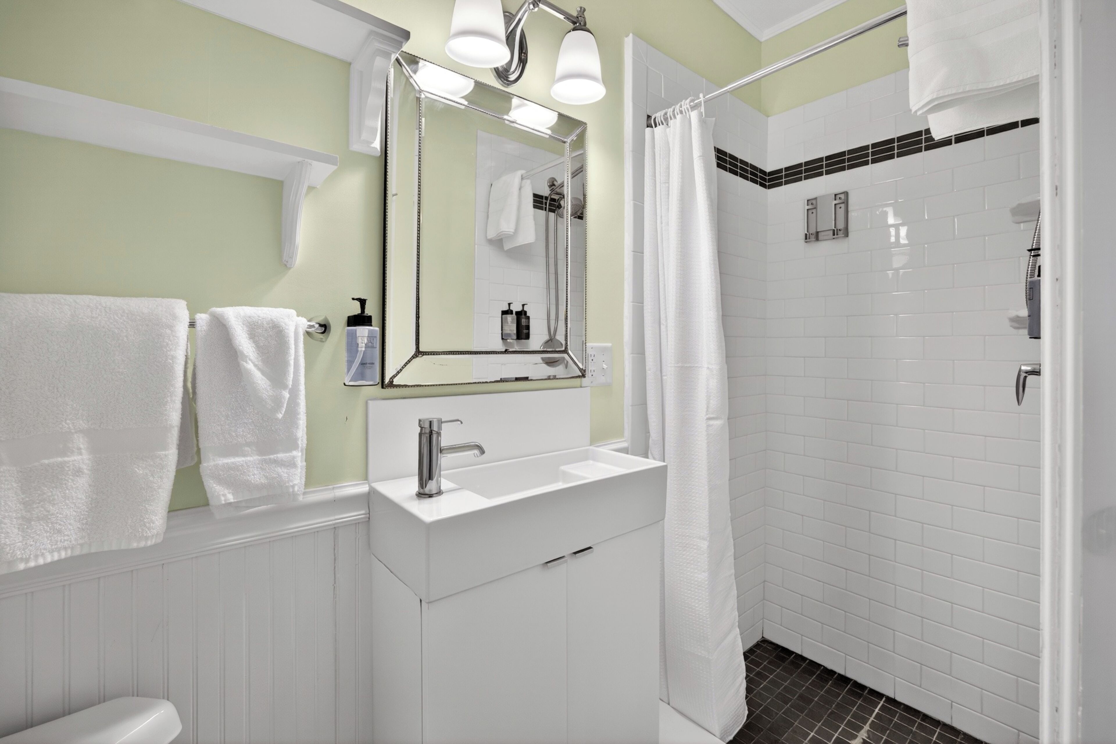 A bathroom with a white sink, mirror, and shower curtain.