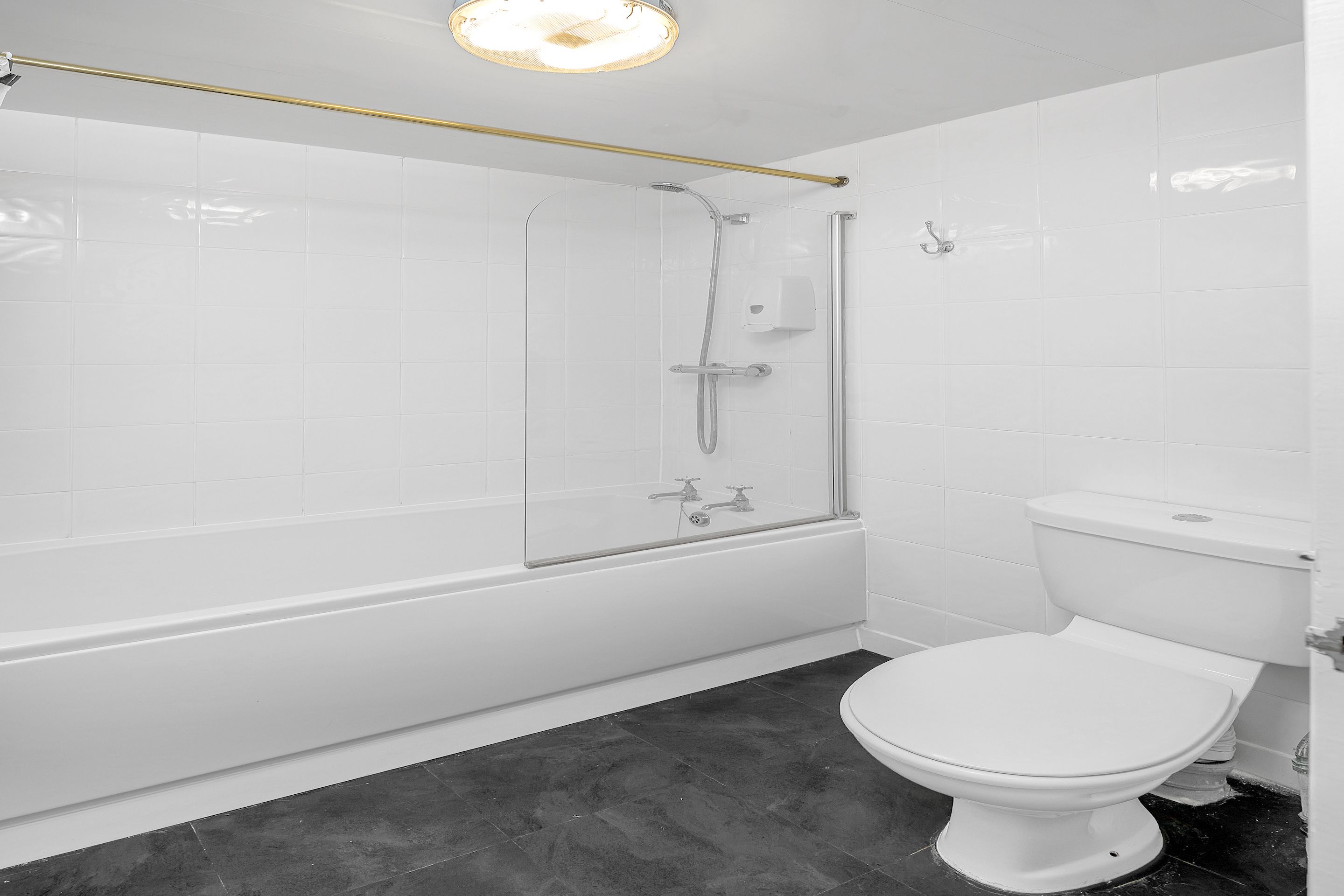 Een badkamer met een bad, douche en toilet.