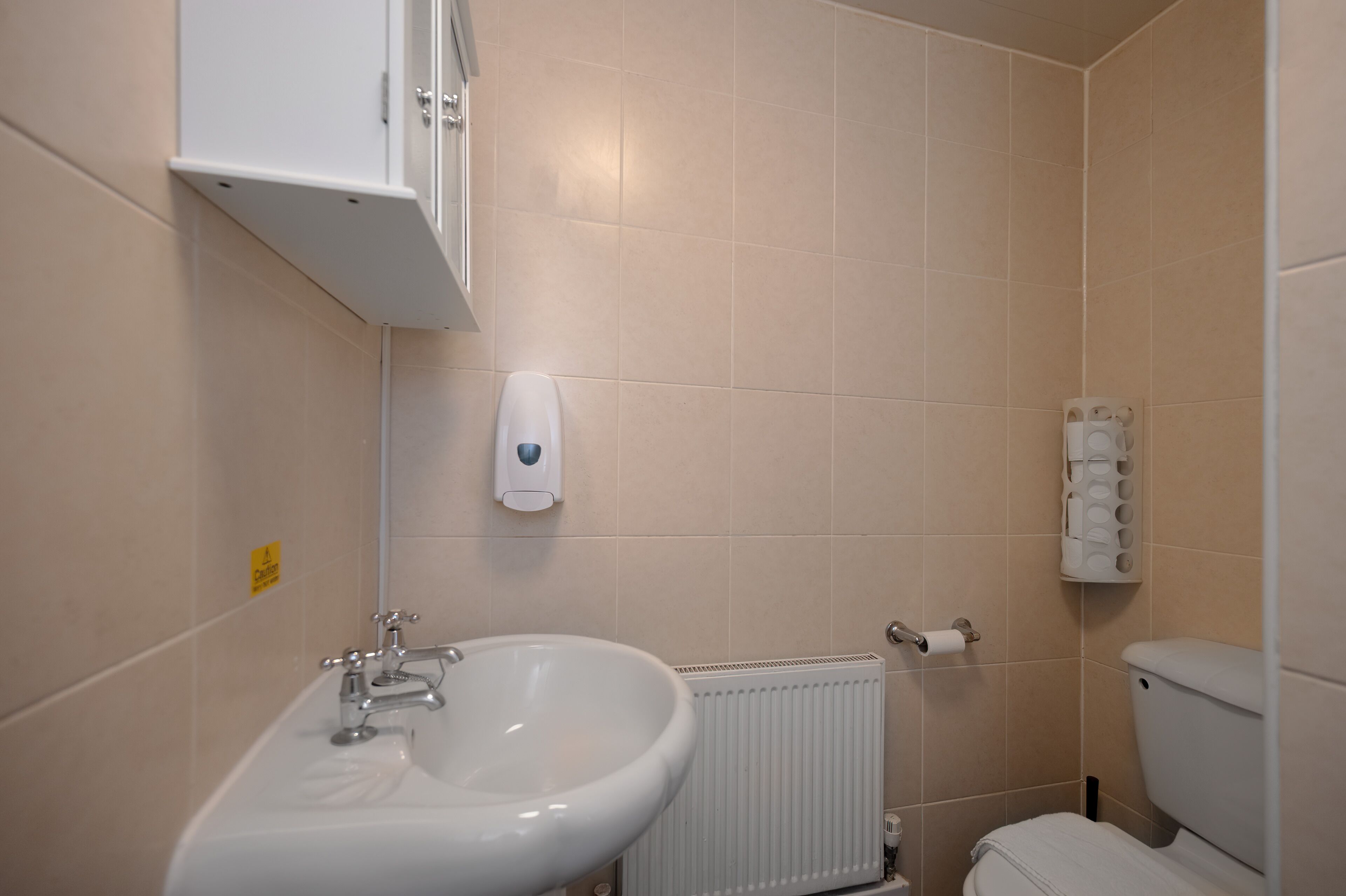 Un baño con lavamanos, inodoro y armario de almacenamiento.