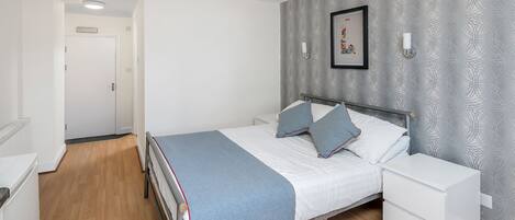 A bedroom with a bed, bedside table, and a nightstand.