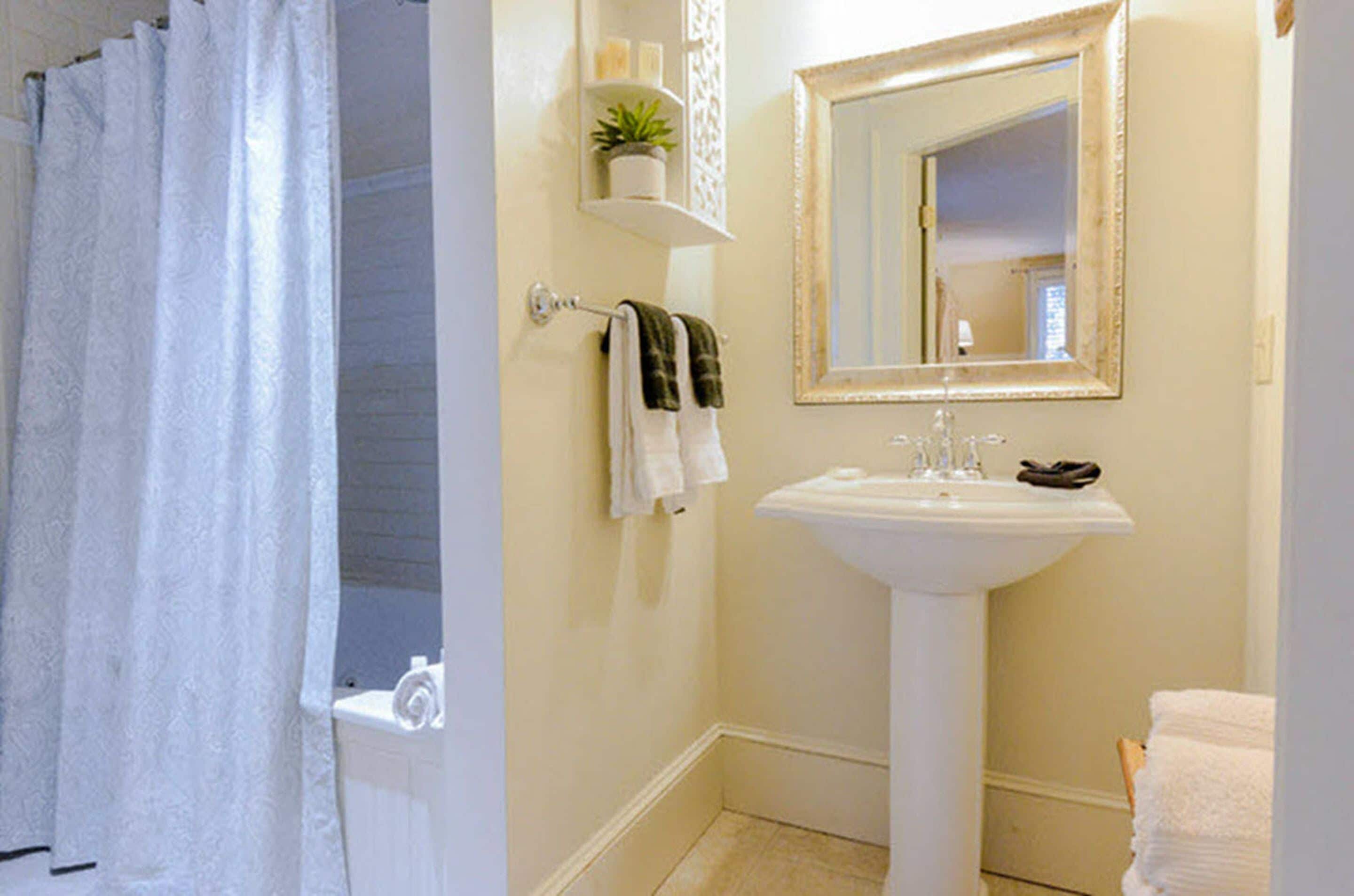 A bathroom with a white sink, a mirror, and a towel rack.