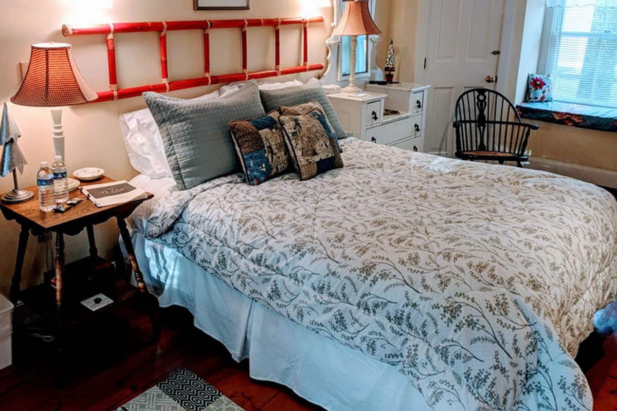 A bedroom with a large bed, bedside tables, a chair, and a window with blinds.