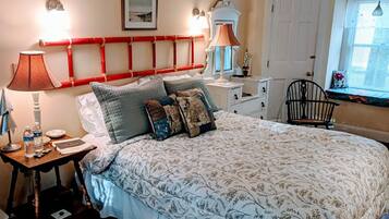 A bedroom with a large bed, bedside tables, a chair, and a window with blinds.