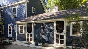 A house with a covered porch, potted plants, and outdoor seating. - Elms of Camden (Camden)