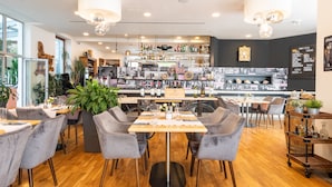 A modern restaurant with a bar area, wooden flooring, and grey upholstered chairs. - Hotel Troja (Prague)