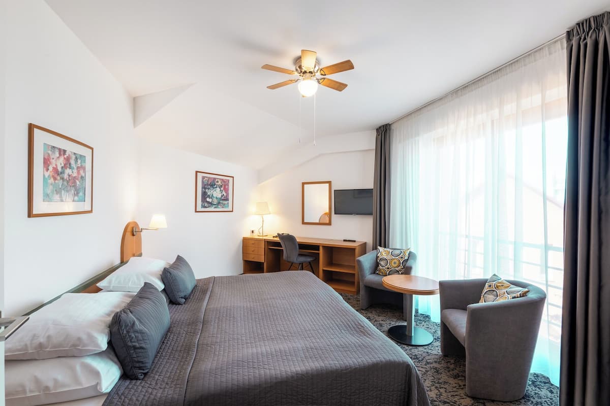A hotel room with a bed, desk, chair, and a television.