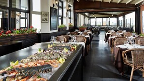 A seafood display in a restaurant with wicker chairs and tables, large windows, and a high ceiling.