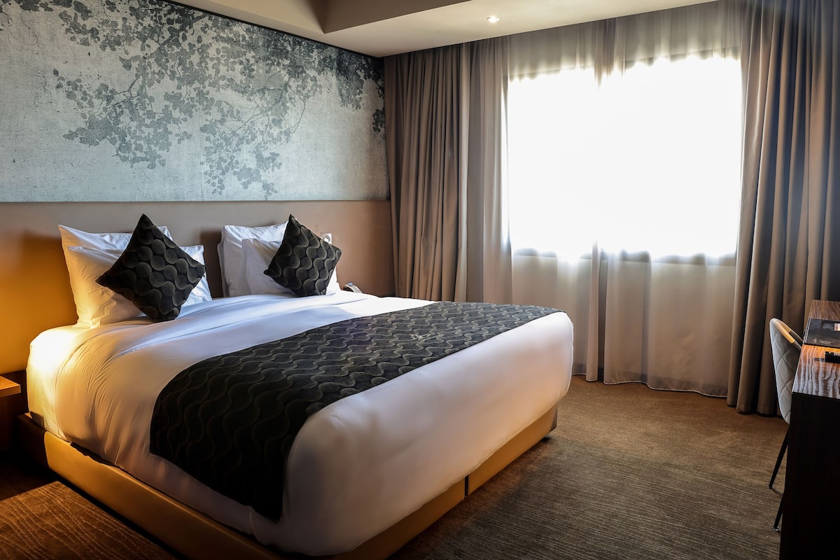 Una habitación de hotel con una cama grande, un escritorio y vistas al exterior a través de la ventana.