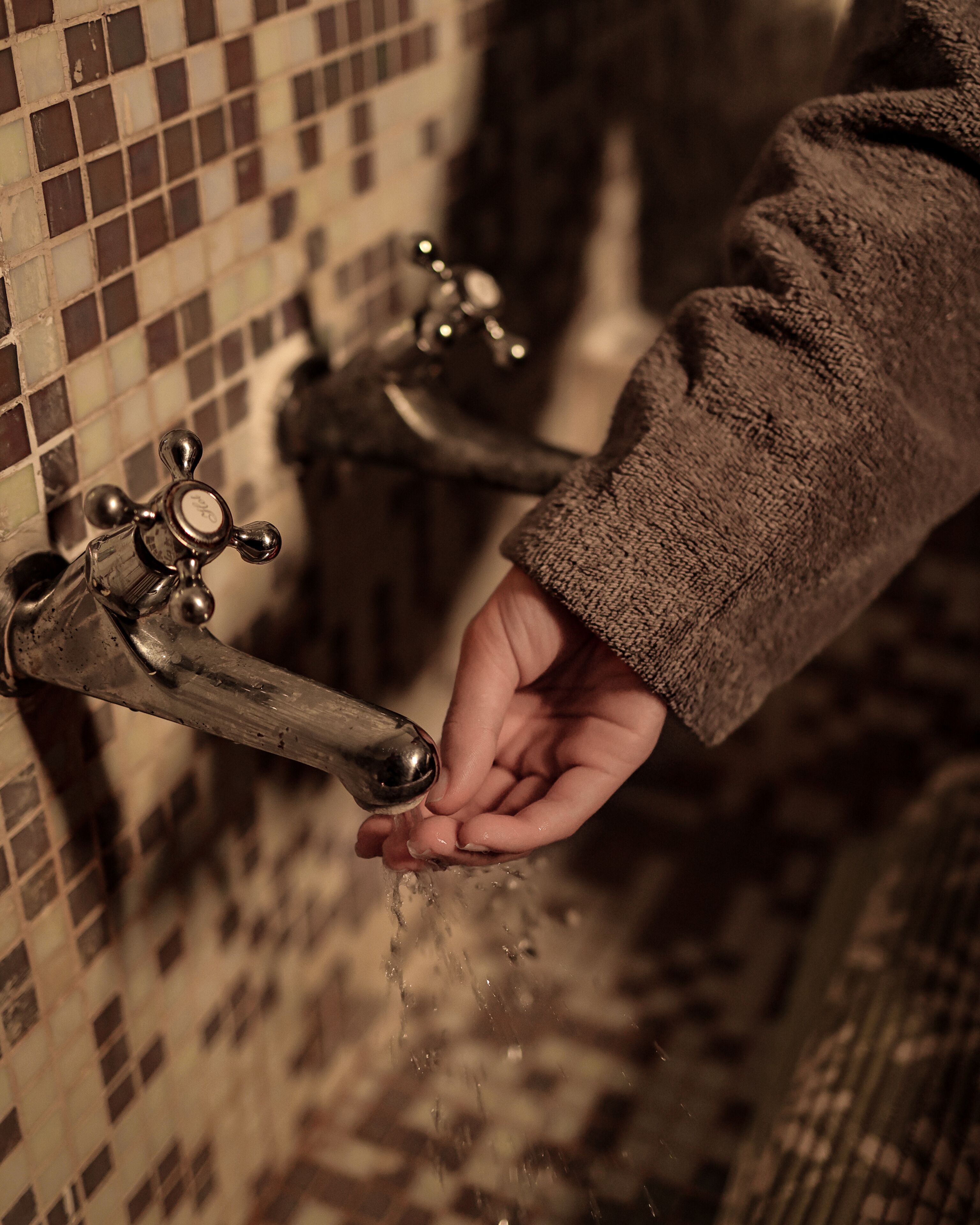 A hand reaching out to a tap with water flowing.
