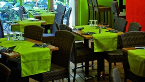 A restaurant with green walls, a large yellow lamp, and a table with chairs.