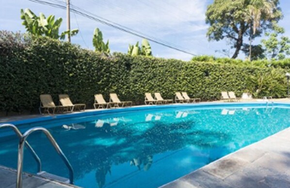 A swimming pool with lounge chairs and a hedge. - Hotel Vila Rica Campinas (Campinas)