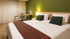 Una habitación de hotel con una cama grande, un escritorio y una silla.