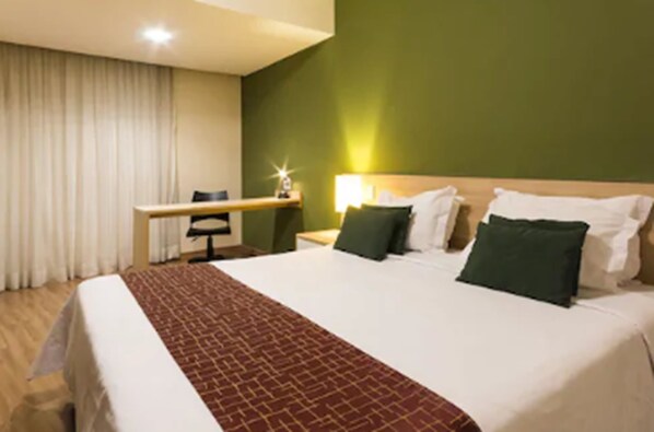 A hotel room with a large bed, a desk, and a chair. - Hotel Vila Rica Campinas (Campinas)