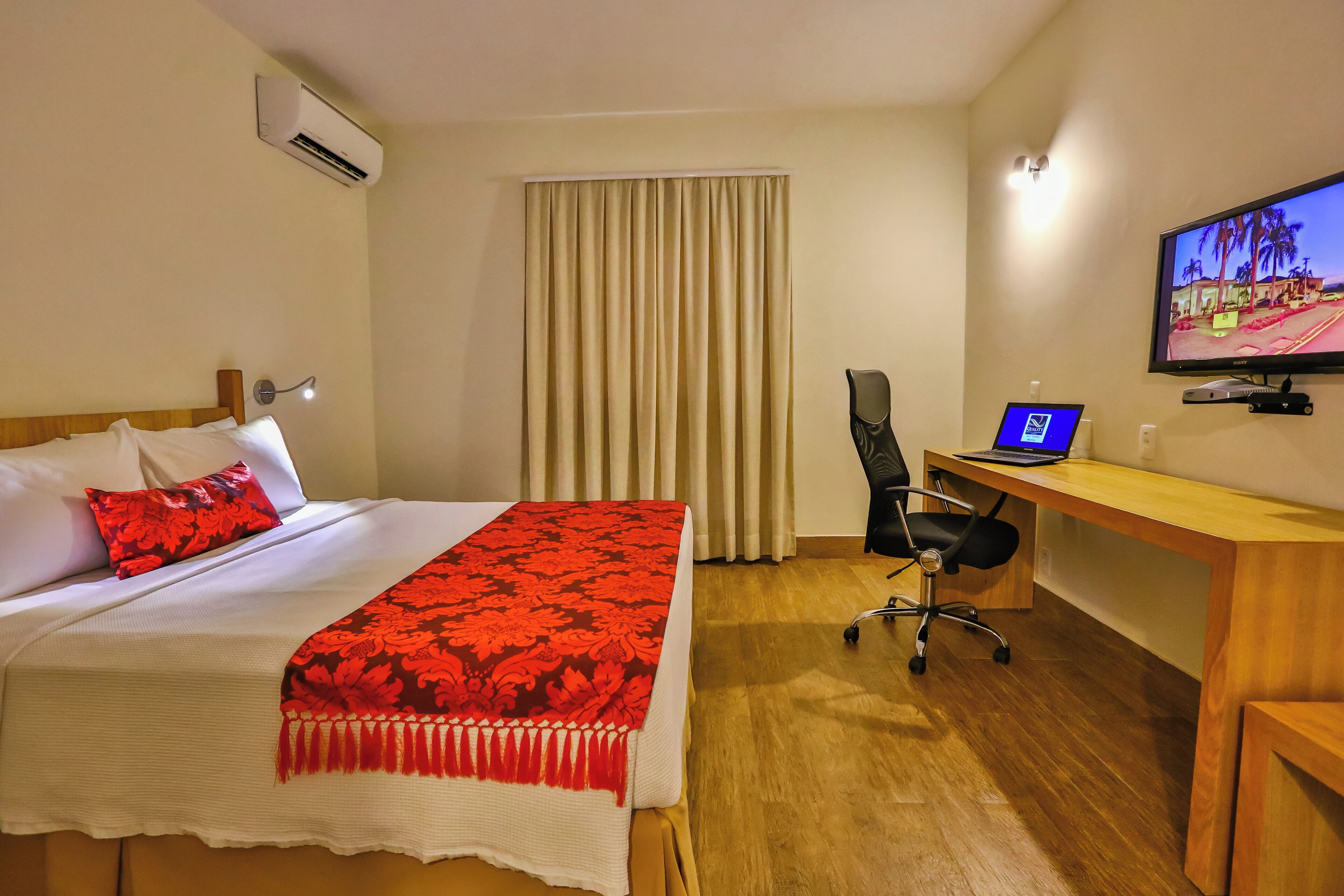 Une chambre d’hôtel équipée d’un lit, d’un bureau, d’une chaise, d’une télévision et d’un appareil de climatisation.