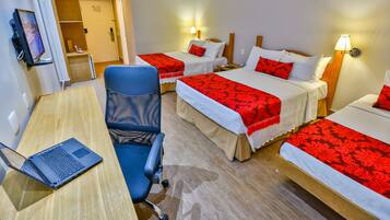 Quarto de hotel com duas camas, uma escrivaninha com um laptop, uma cadeira e uma televisão.