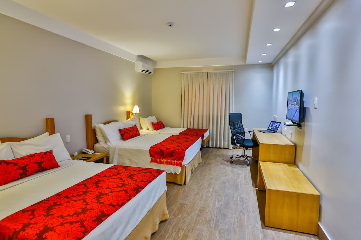 A hotel room with two beds, a desk, a chair, a TV, and a window with curtains.