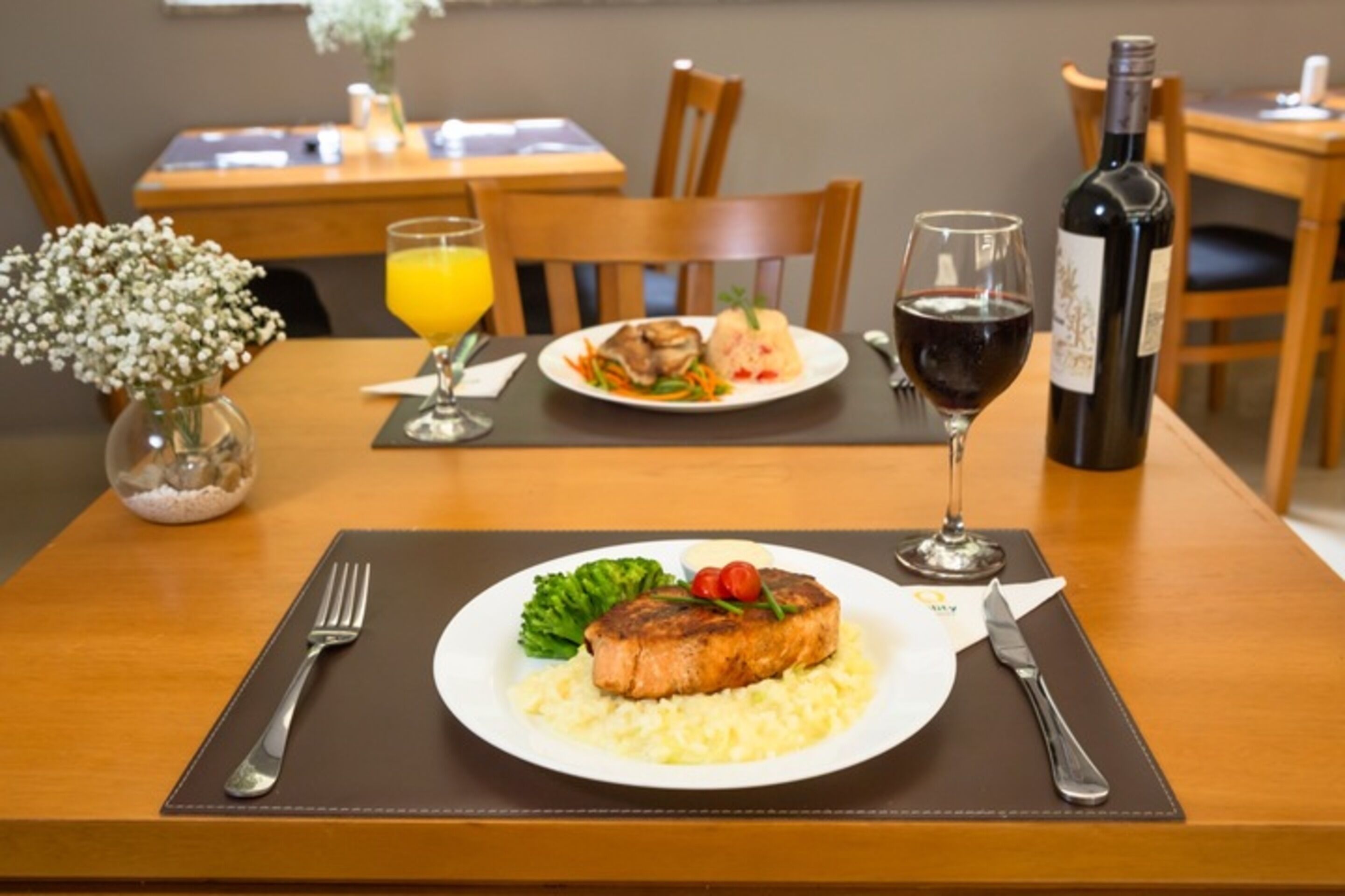 Uma mesa de jantar com um prato de comida, uma garrafa de vinho e uma taça de vinho.