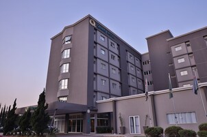 Un hotel de varios pisos con un diseño moderno, que presenta un llamativo letrero de "Quality Hotel" en la fachada.