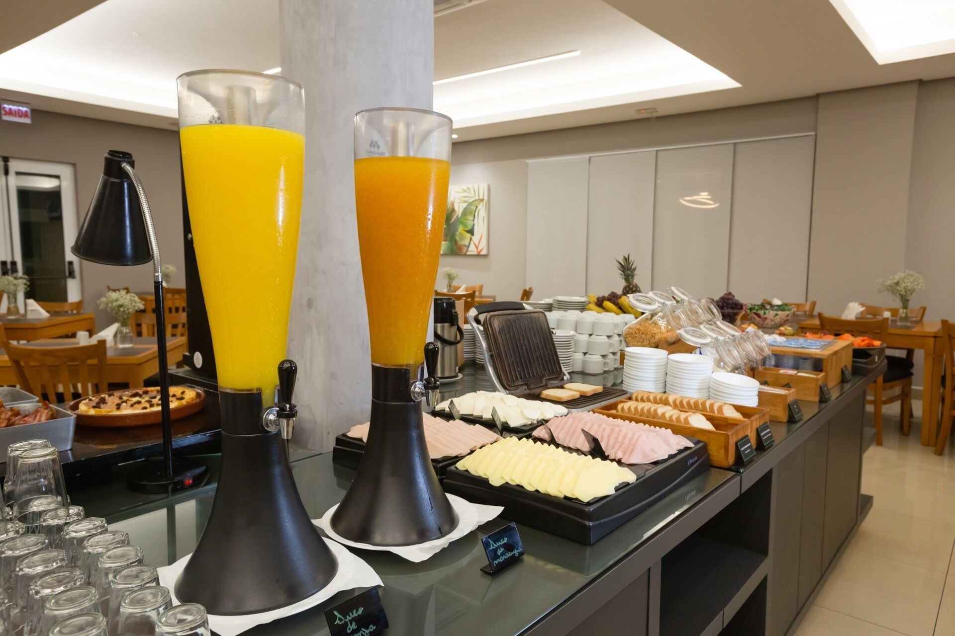 A buffet area with juice dispensers, a waffle maker, and various food items.